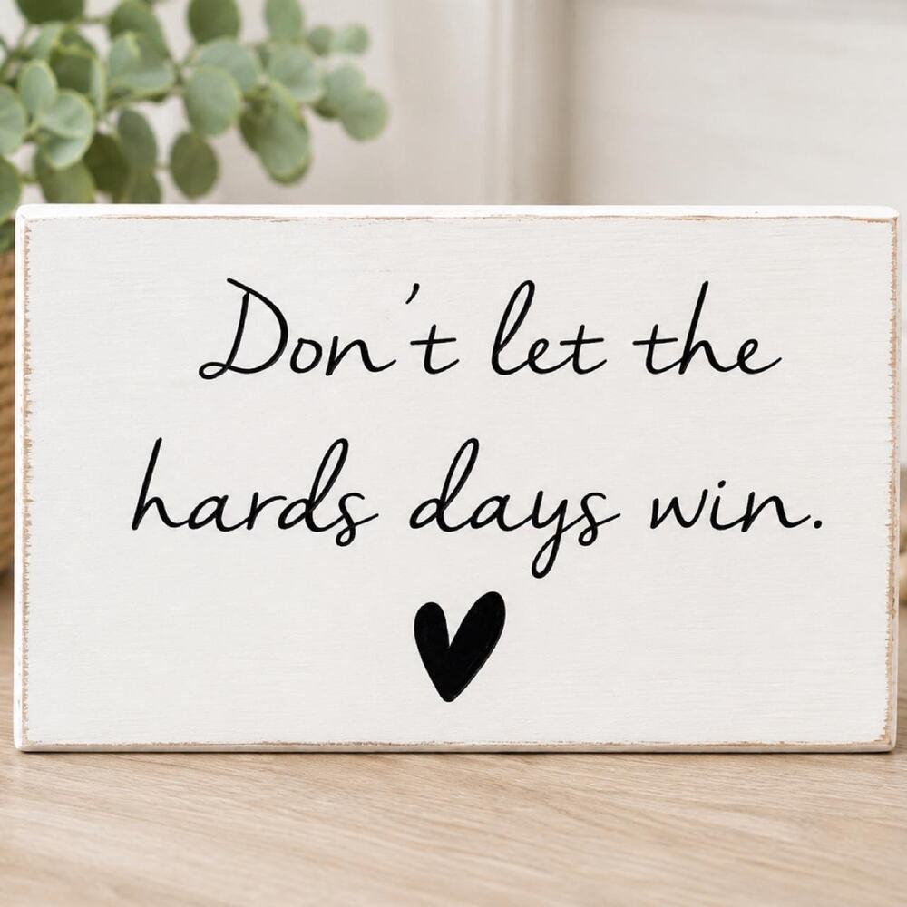 White wooden sign 'Don't let the hards days win.' with a black heart